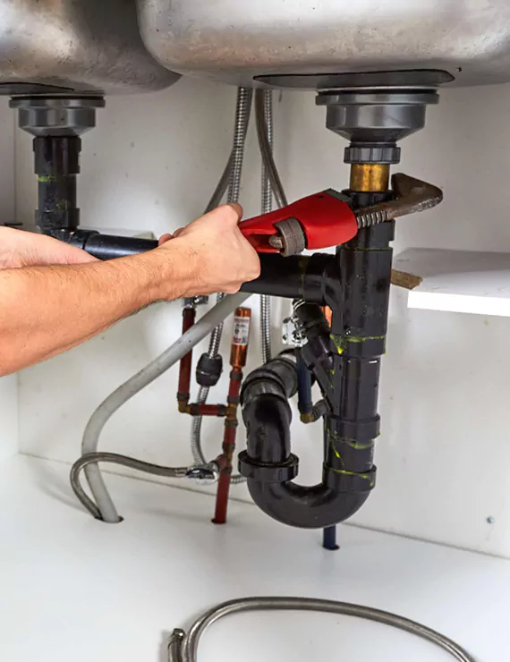 Professional plumber in Dunstable repairing boiler and fixing blocked drain with tools